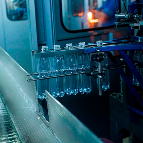 Botellas de plástico saliendo de una máquina de soplado